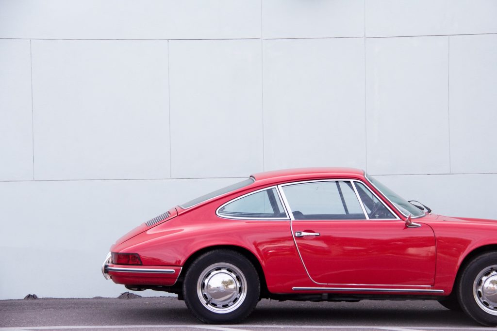 a red car parked in front of a white wall