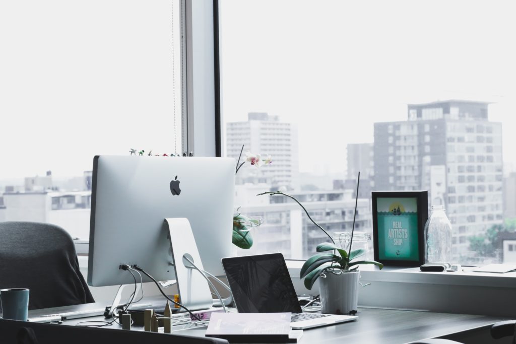 a desk with computers and a laptop