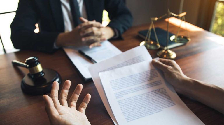 a group of people sitting around a table with papers and a cup