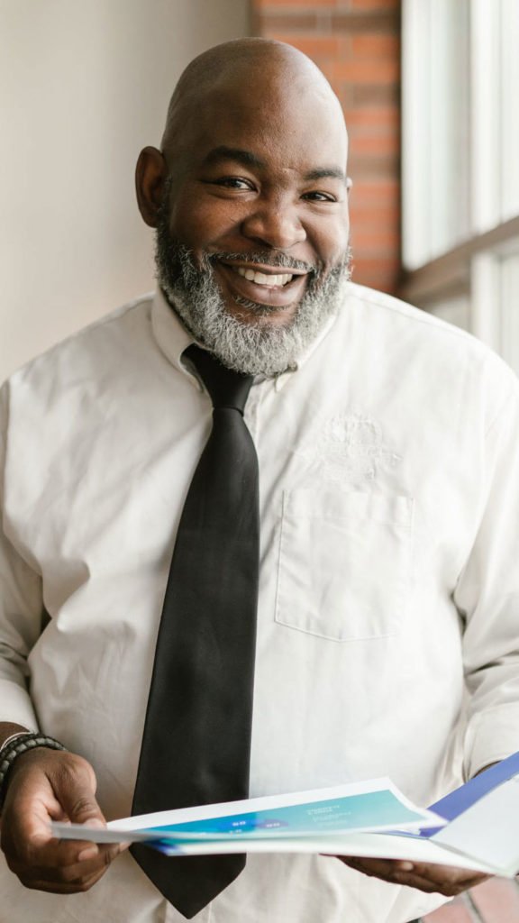 a man in a white shirt and black tie holding a book