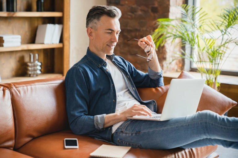 a person sitting on a couch and using a laptop