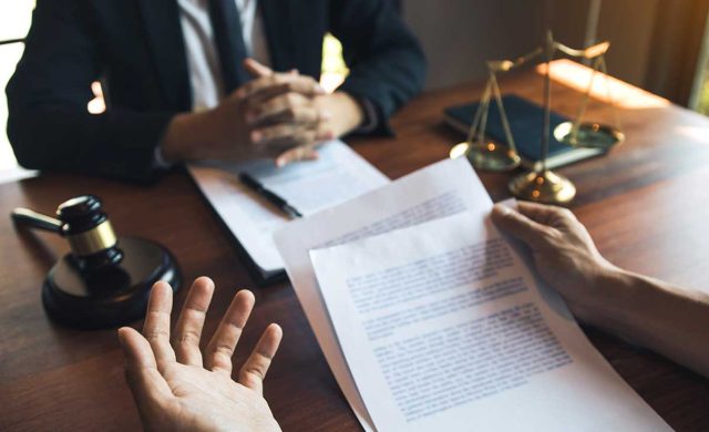 a group of people sitting around a table with papers and a cup